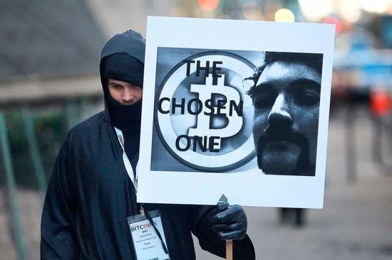 2015年，罗斯·乌布利希在纽约参加庭审时的一位抗议者（举着牌子）。法警局第一次拍卖的加密货币就是缉毒行动从罗斯·乌布利希身上缴获的比特币。Spencer Platt—Getty Images