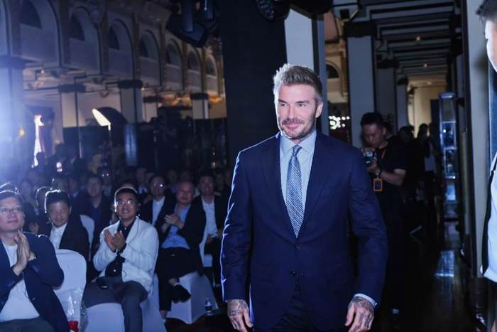 A person in a suit walking down a stageAI-generated content may be incorrect.
